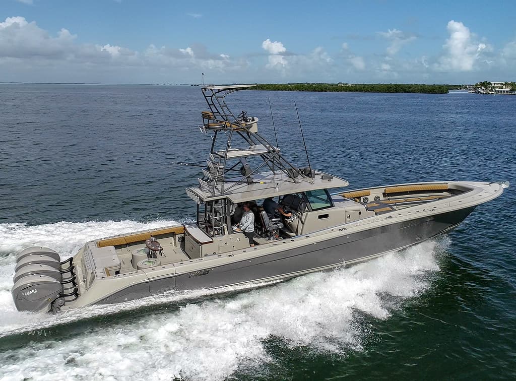 Dark metallic center-console sport fishing boat underway with outboards