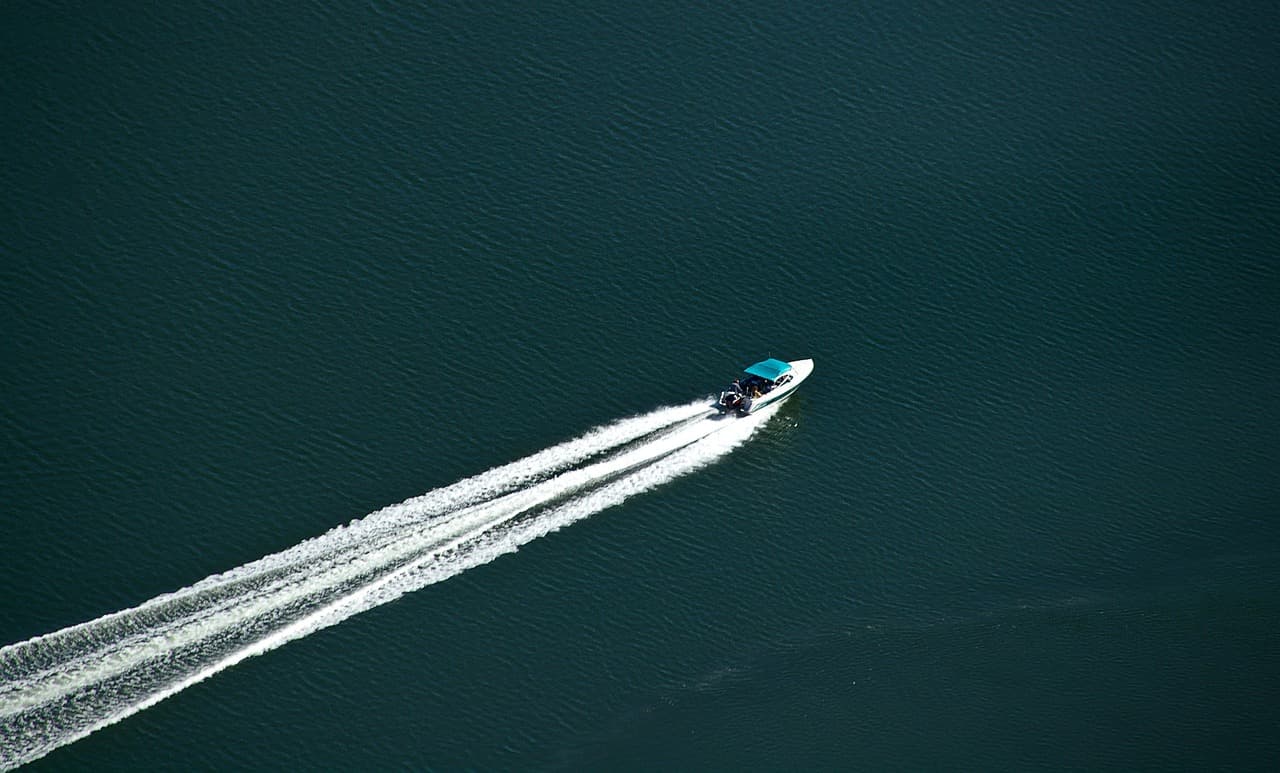 White center-console boat running across deep blue water leaving a wake